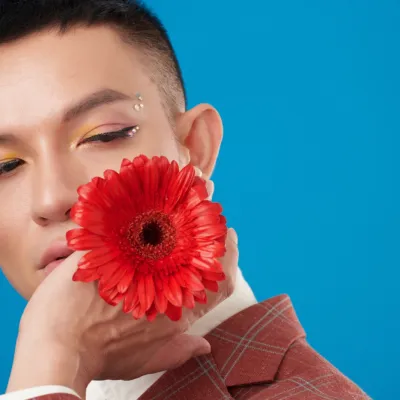Model Poses With Red Flower Against Blue Backdrop 2026 03 18 05 34 31 Utc